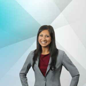 Fatema Raza, smiling in a corporate headshot while wearing a grey blazer with a burgundy blouse.