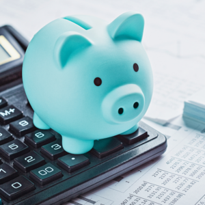 Blue piggy bank on a calculator with financial documents in the background depicting savings of an accountable plan.