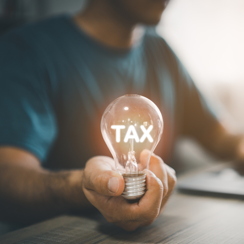 Man hand holding light bulb while working on laptop and mobile phone. With tax messages, conveys SALT tax deductions at the end of the year.